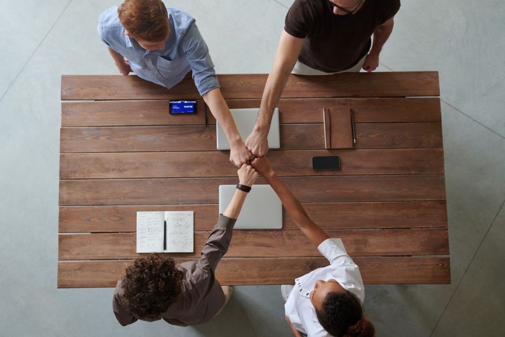 Pessoas se cumprimentando sobre a mesa — indicação e parceria no Clube de Indicações APP019